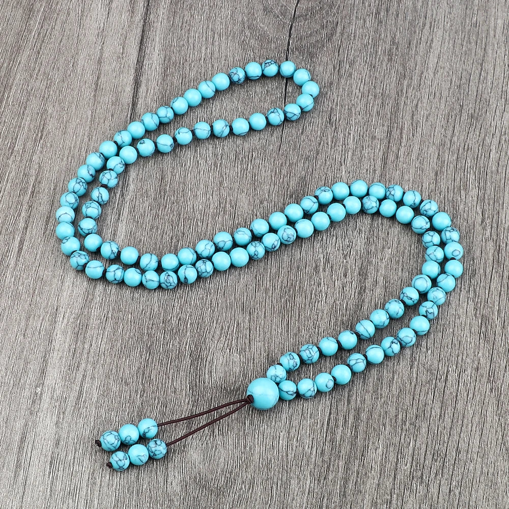 Eine Kette aus türkisblauen Natursteinperlen liegt auf einer grauen Holzoberfläche.