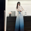 Une femme modélise un trench-coat à plis bleu clair et blanc dans un studio.