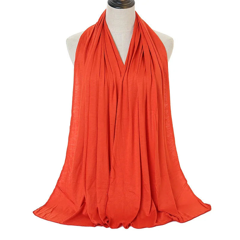 A vibrant orange soft modal jersey hijab scarf draped around a mannequin's neck.