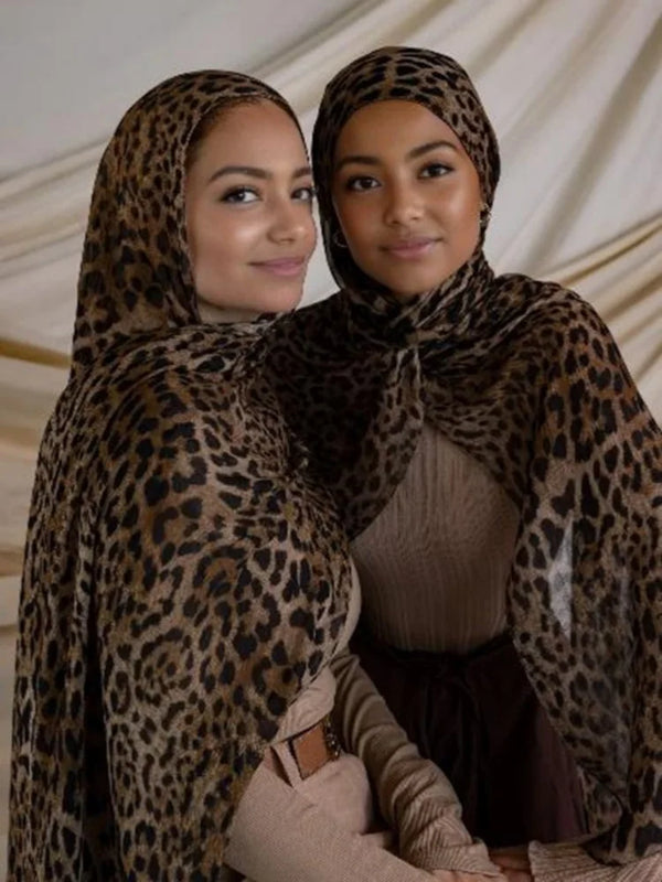 Two women wearing leopard print hijabs posing together