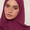 Gros plan d'une femme portant un foulard hijab modal magenta foncé.