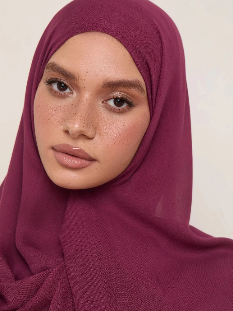 Gros plan d'une femme portant un foulard hijab modal magenta foncé.