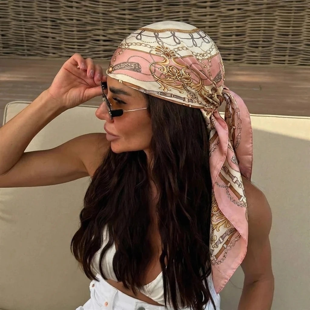 A woman wearing an elegant silk dot print scarf tied around her hair and neck.