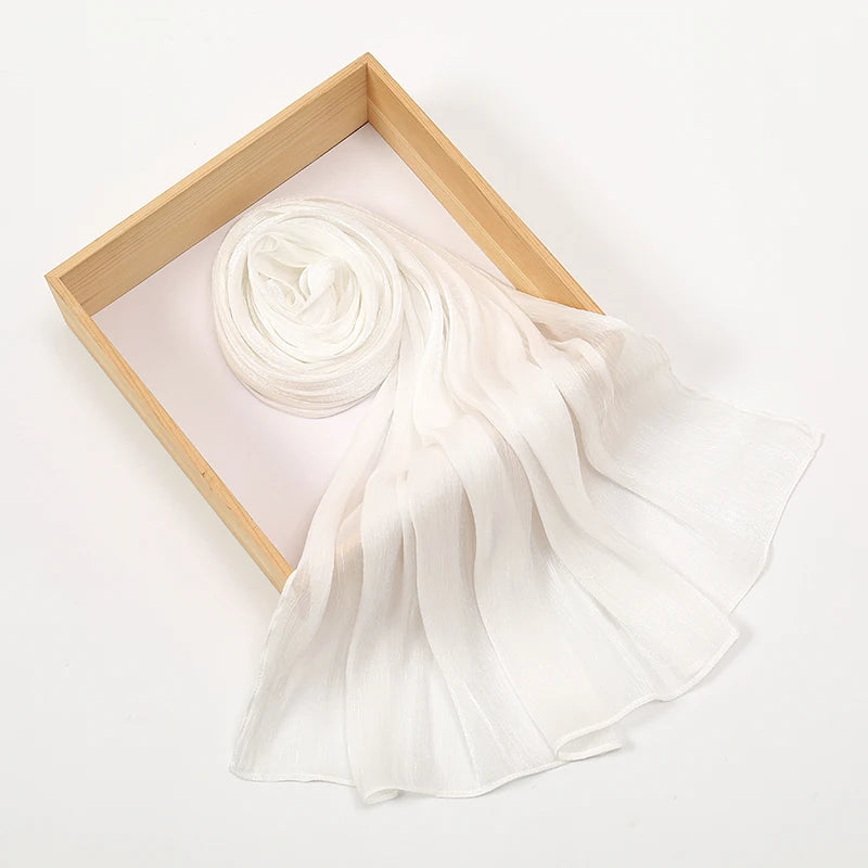 Un pañuelo de chifón brillante blanco y arrugado se exhibe dentro de un marco de madera.
