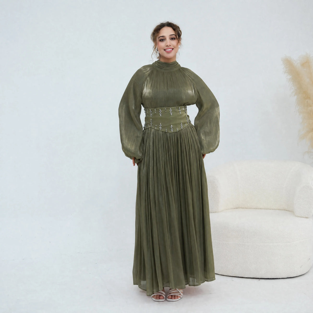 Une femme portant une abaya longue à manches olive avec une ceinture ornée.