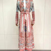 Eine Frau trägt einen langen, fließenden, plissierten Abaya-Cardigan in floralen Mustern in Rosa, Rot und Blau.