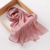 Étoffe de mousseline rose rosée et scintillante, fluide, drapée dans un cadre en bois.
