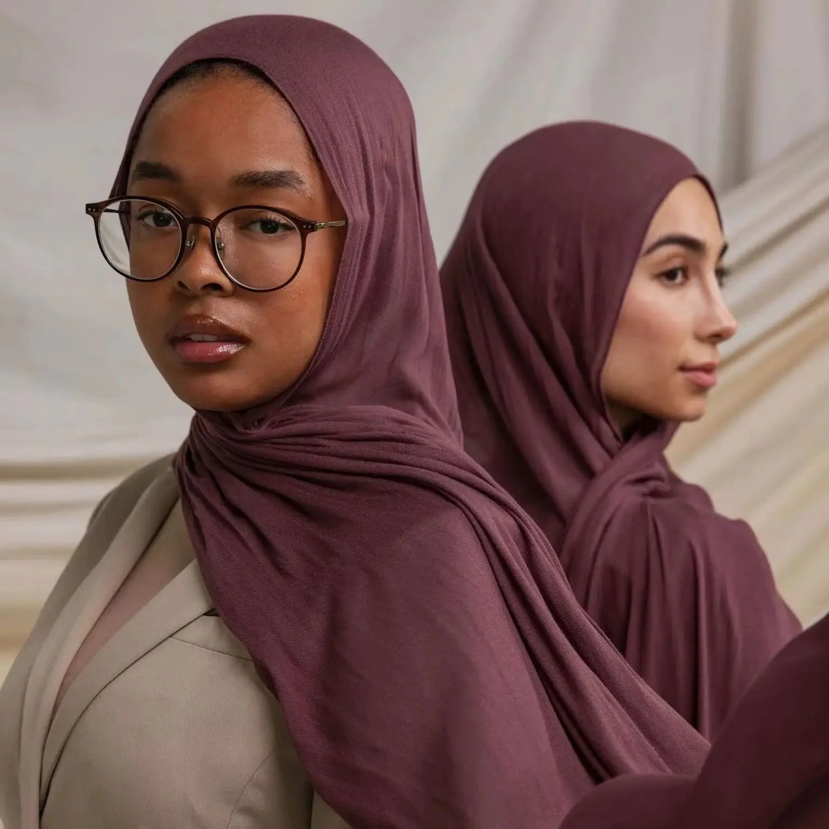 Une femme portant un foulard modal uni couleur mauve poussiéreuse et une tenue beige.