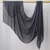 Pañuelo semitransparente azul oscuro con lunares blancos colgado en un perchero de madera.
