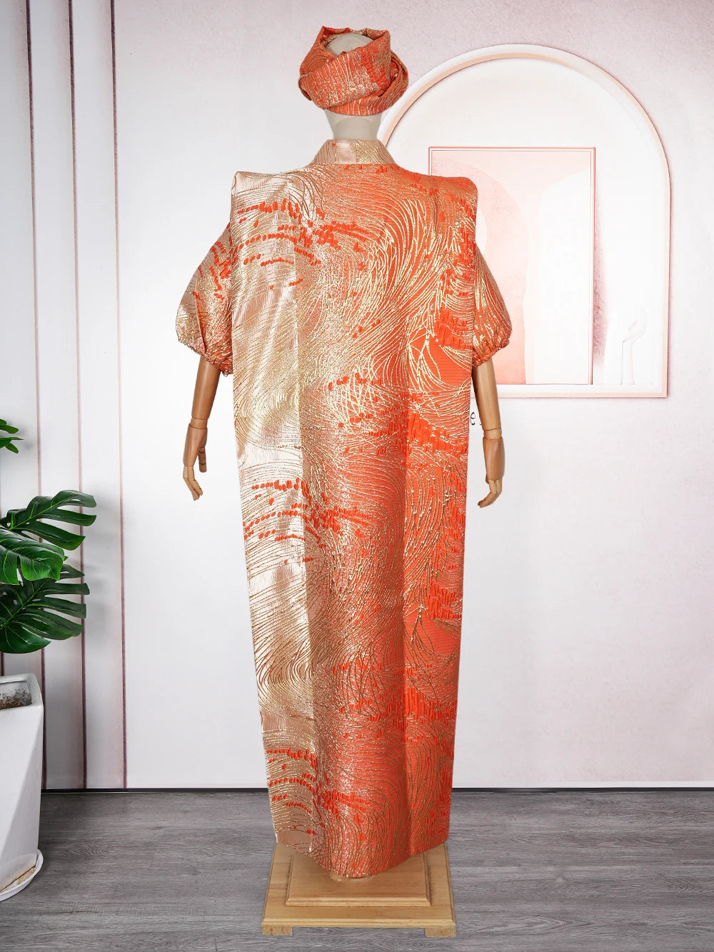 A woman wearing an orange satin kaftan abaya with gold embroidery displayed on a mannequin.