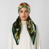 A woman wearing an elegant satin silk instant hijab scarf with green and orange floral patterns.