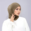 Eine Frau trägt einen beigen Instant-Turban Hijab, eine Untercap-Bonnet und ein weißes Langarm-Top.