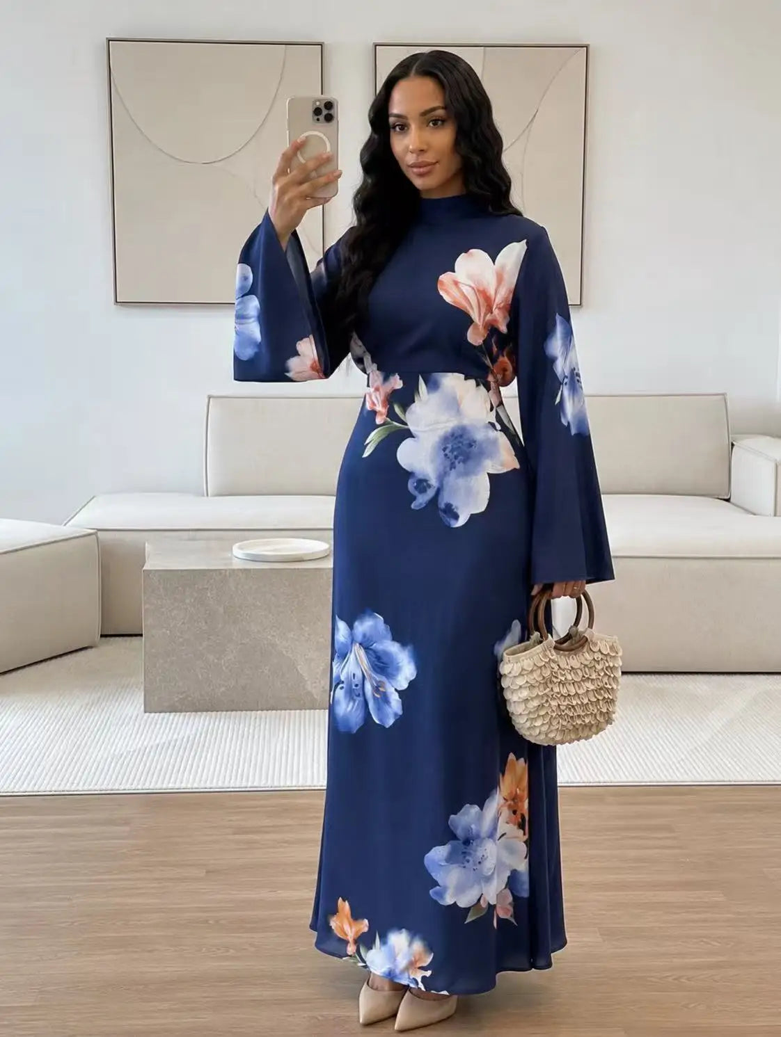 Eine Frau modelliert ein marineblaues Abaya-Kleid mit großen floralen Mustern in rosa und blau vor hellem Hintergrund.