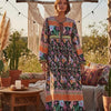 Eine Frau modelliert ein langes Blumenmaxi-Kleid mit farbenfroher Stickerei im Freien.