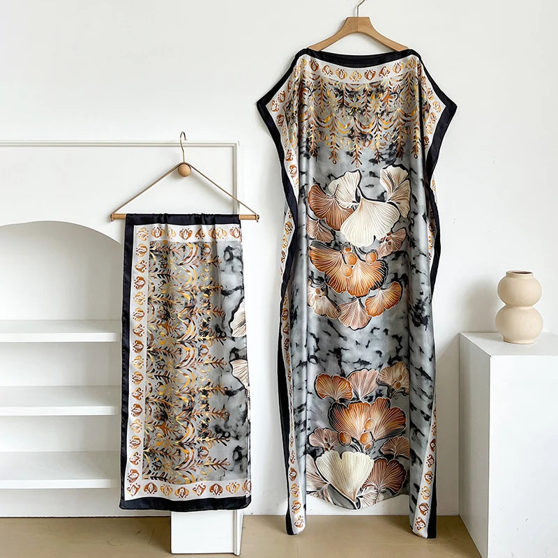 Langes Kaftan-Kleid mit schwarz-grau gemustertem Stoff und goldenen Akzenten, auf einem Bügel.