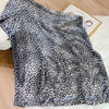 A black and white leopard print silk satin neckerchief hijab scarf draped on a light surface.