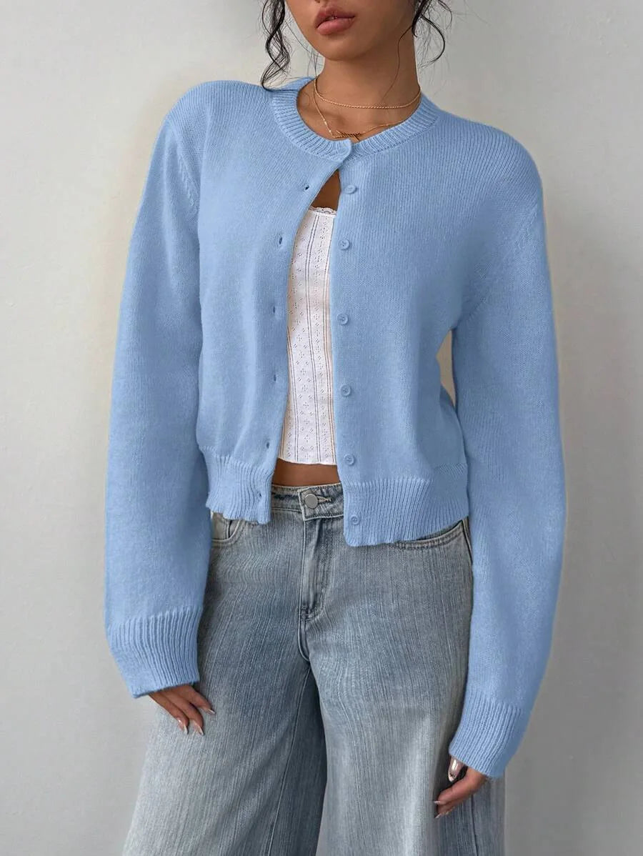 Une femme portant un pull tricoté bleu clair par-dessus un haut blanc et un jean en denim.