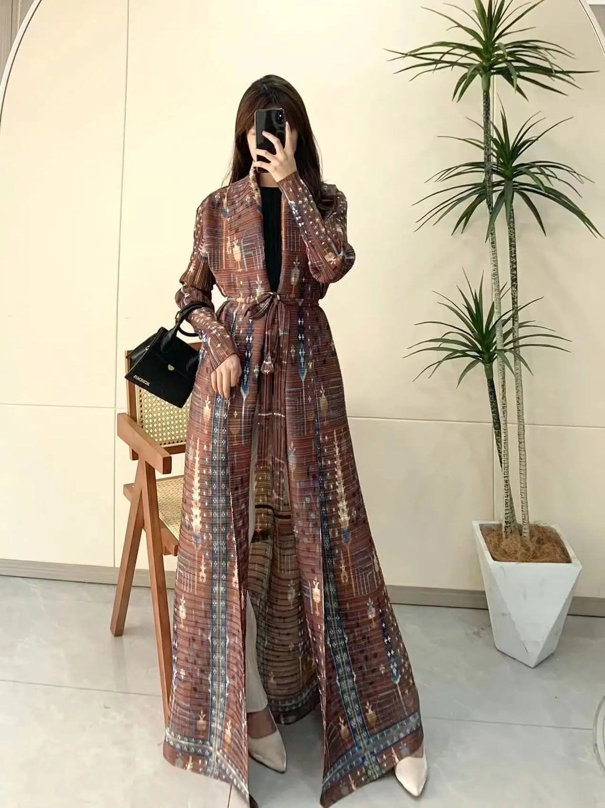 Une femme modélise un long trench à motifs avec manches longues et taille à la ceinture dans des tons terreux.