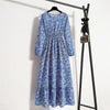 Langes blaues Blumenmuster-Maxikleid hängt an einem schwarzen Kleiderständer.