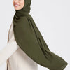 A woman wearing a olive green chiffon matching inner scarf set and a beige coat.