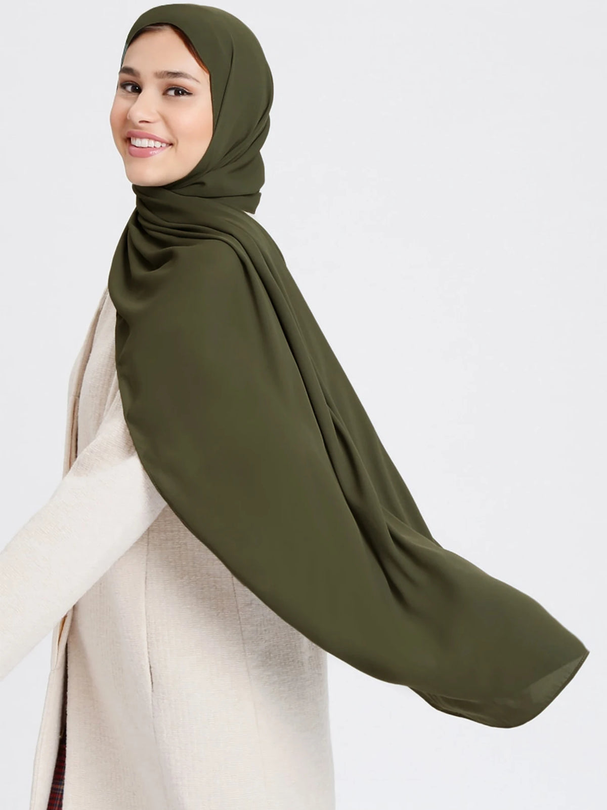 A woman wearing a olive green chiffon matching inner scarf set and a beige coat.