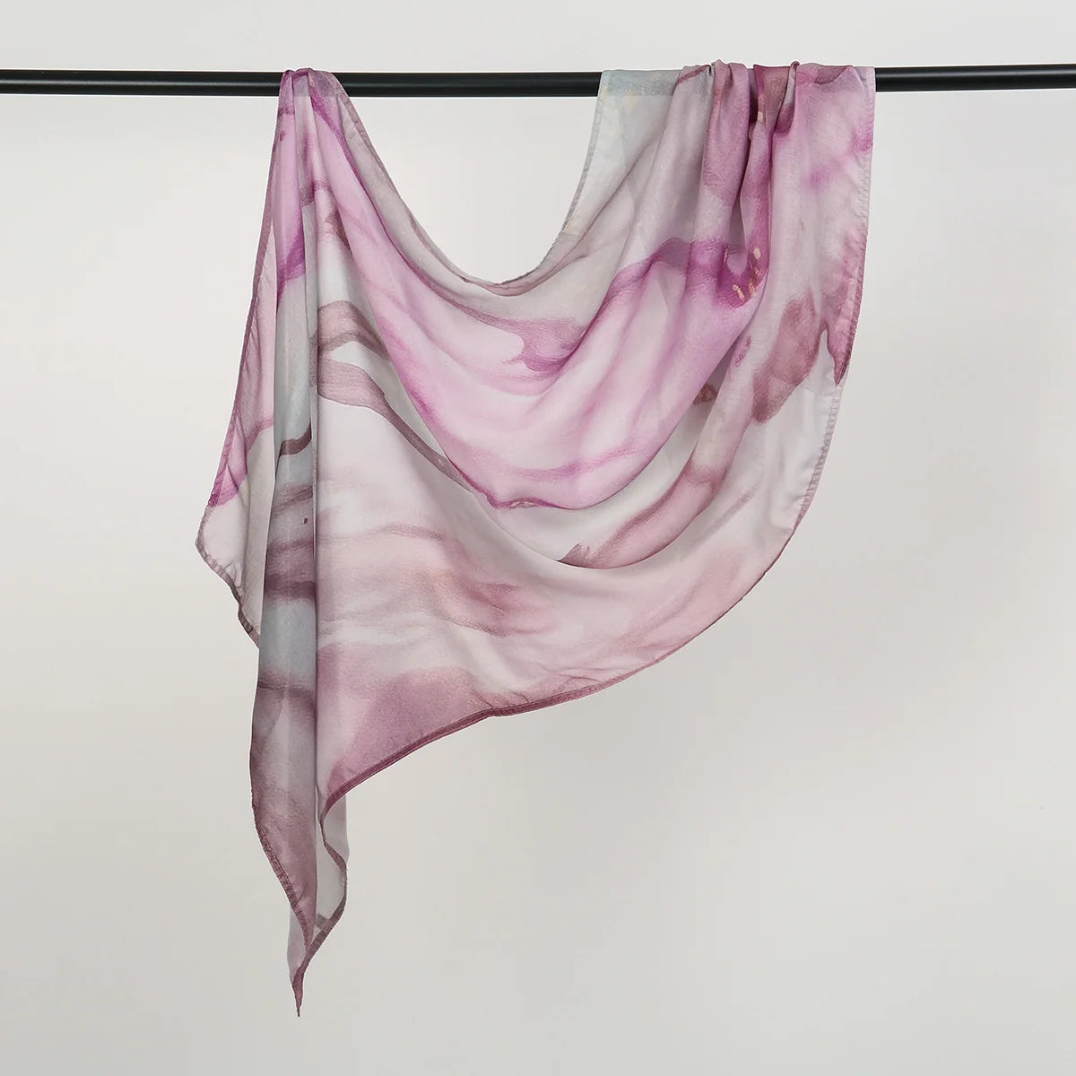 Durchsichtiger, fließender Schal mit aquarelligen rosa und lila marmorierten Mustern an einem schwarzen Haken.