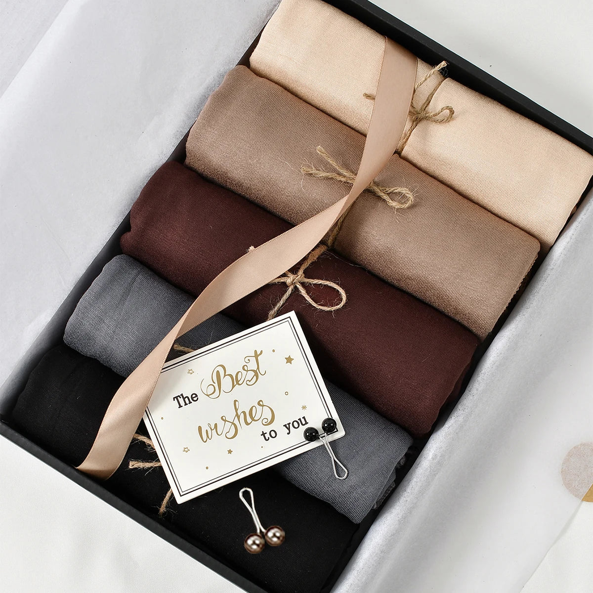 Un ensemble de foulards hijab en mousseline de coton élégants dans des tons neutres, incluant un foulard beige noué avec de l