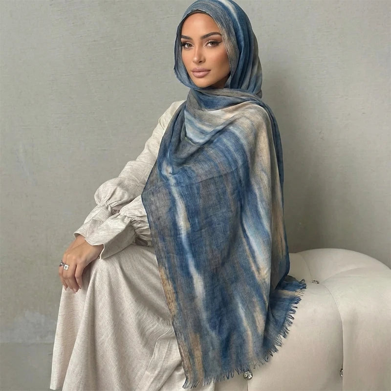 Una mujer modela un pañuelo floral de acuarela azul y gris drapeado sobre su hombro.