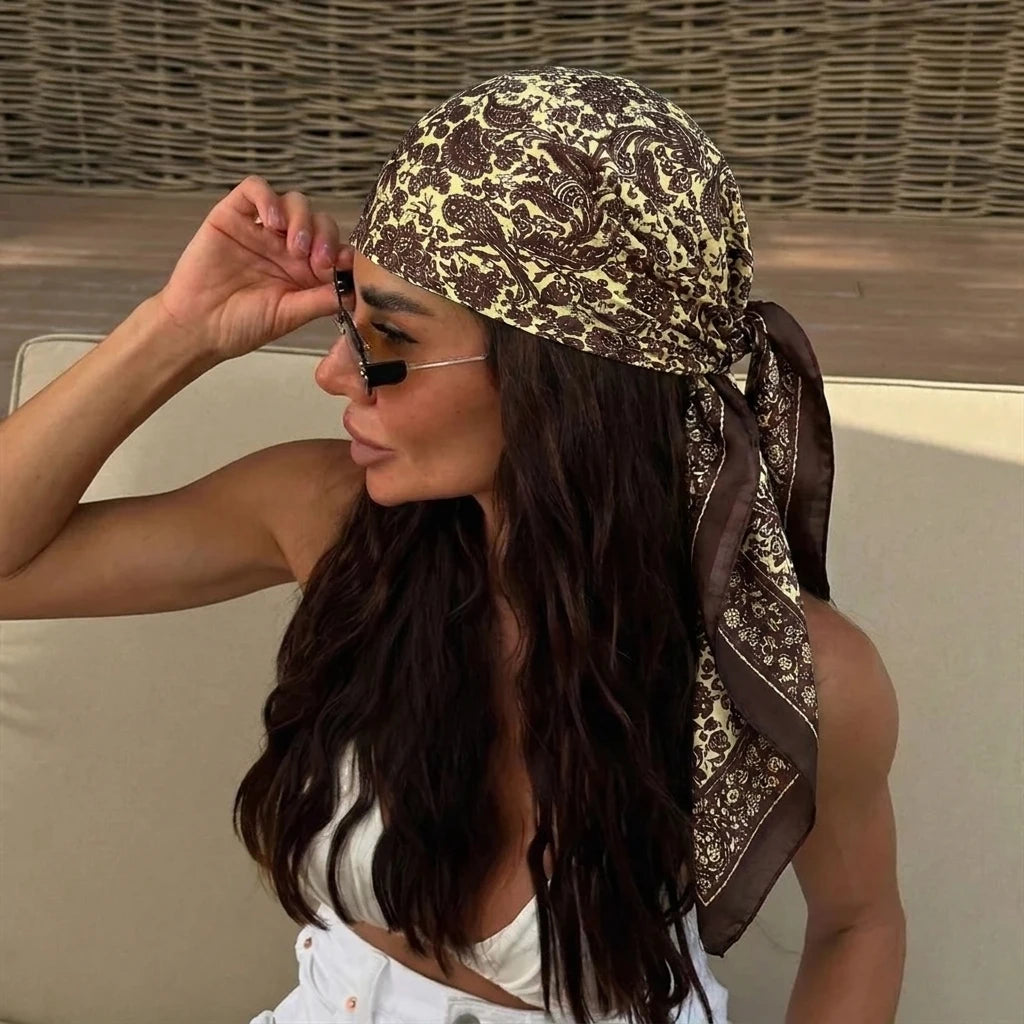 A woman wearing an elegant silk dot print scarf tied around her hair and neck.