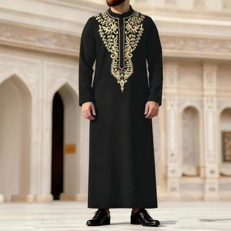 Hombre vistiendo una jubba thobe casual negra bordada con detalles dorados en un interior grandioso.