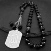 Porte-clés islamiques arabes en perles noires de Allah, exposés sur une surface sombre.