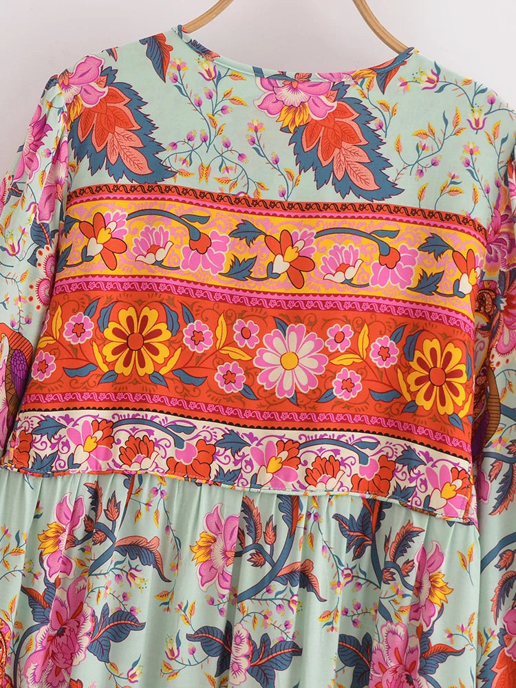 Vestido largo bohemio color menta claro con estampados florales vibrantes en rosa, naranja y púrpura.