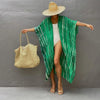 Model in a green patterned kimono cover-up over a white dress and straw hat