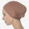 A close-up profile view of a woman wearing a dusty rose breathable cotton underscarf with an elastic fit.