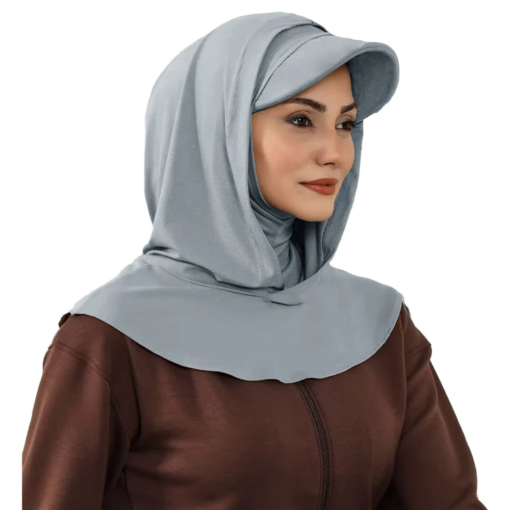 Une femme portant un bonnet hijab couvrant gris clair et un haut marron.