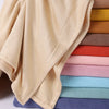 Una pila de conjuntos de hijab de dos piezas a juego en tonos pastel y tierra, mostrando la textura de la tela.