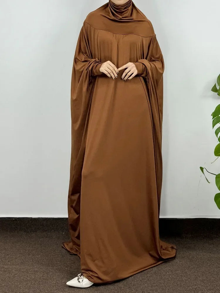 Una mujer vistiendo una elegante abaya marrón, larga hasta el suelo y con capucha.
