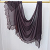 Hijab de encaje morado oscuro drapeado sobre un percha dorada.