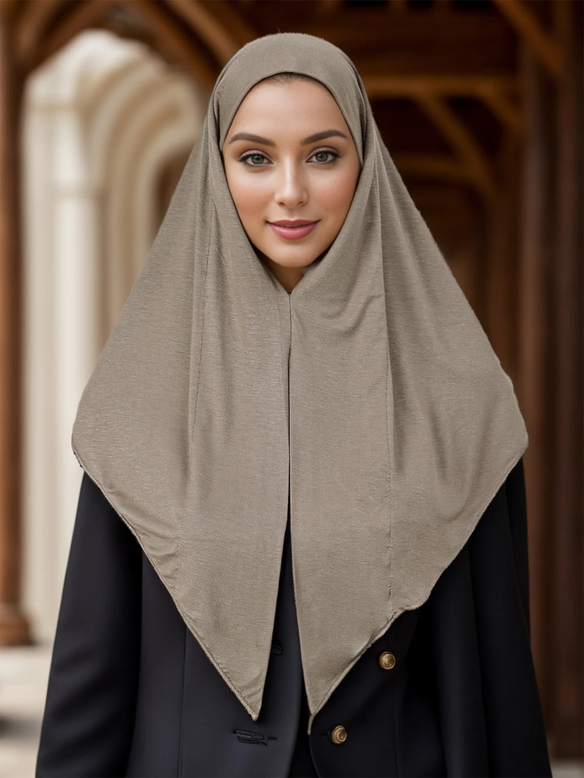 Une femme portant un foulard instant beige et un blazer noir dans un intérieur.