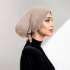 Eine Frau trägt einen beige drapierten Hijab mit Strassverzierung und einem schwarzen Samt-Oberteil.