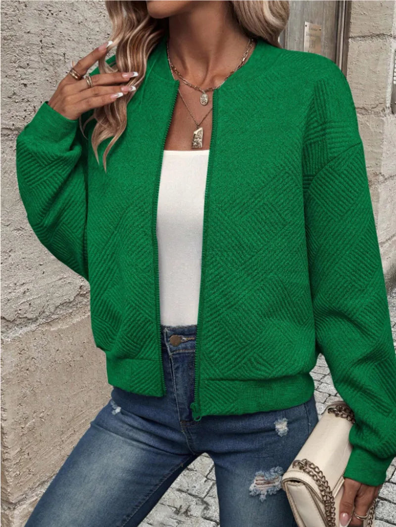 Une femme portant une veste à fermeture éclair vert vif sur un haut blanc et un jean bleu.
