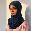 Eine Frau trägt einen dunkelblauen Instant-Fold-Hijab mit verstecktem Reißverschluss und ein pinkes Oberteil, im Freien.