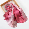Un foulard hijab en soie satinée rose roulé et drapé sur un cadre en bois.