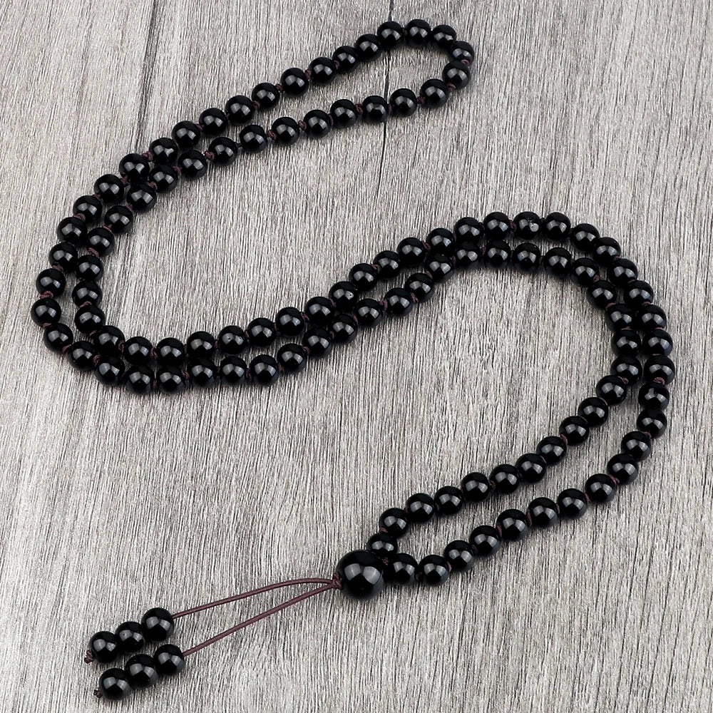 Schwarze Natursteinperlenkette, drapiert auf einer Holzoberfläche.