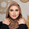 Eine Frau trägt einen einfarbigen braunen Instant fertigen Jersey-Hijabschal und blickt direkt in die Kamera.