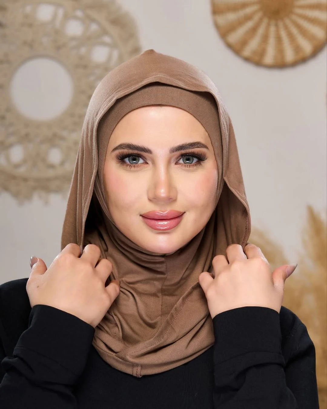 Eine Frau trägt einen einfarbigen braunen Instant fertigen Jersey-Hijabschal und blickt direkt in die Kamera.