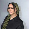 A woman wearing a solid olive green silk satin hijab scarf and black clothing.