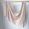 Foulard modal rose pâle uni drapé sur un cintre en bois.