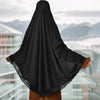 Schwarzer Instant-Hijab mit Spitzenrand, getragen von einer Frau vor städtischem Hintergrund.