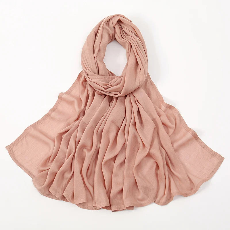 Pañuelo de algodón rayón color rosa empolvado, drapeado alrededor del cuello y los hombros.